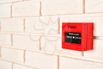 Modern fire call point on brick wall indoors�