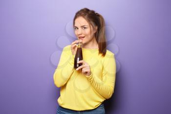 Beautiful young woman with bottle of juice on color background�