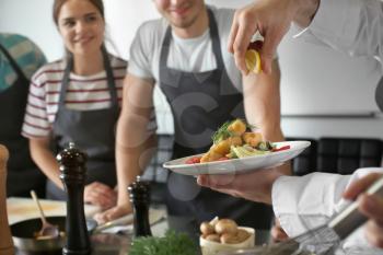 Male chef holding plate with prepared dish during cooking classes�