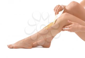 Young woman epilating her leg with liquid sugar on white background�