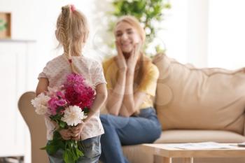 Cute little girl hiding bouquet of flowers for mother behind her back�