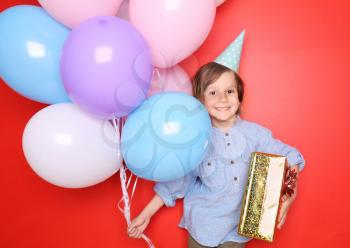 Cute little boy with balloons and gift for his birthday and on color background�