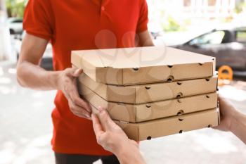 Young man giving pizza boxes to woman outdoors. Food delivery service�