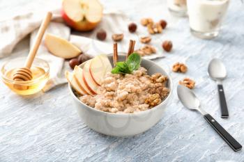 Tasty oatmeal with apple and walnut in bowl on table�
