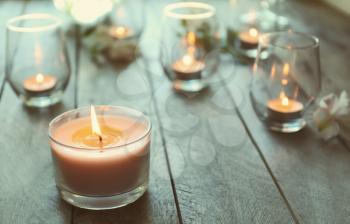 Beautiful burning candles in glasses on wooden table�