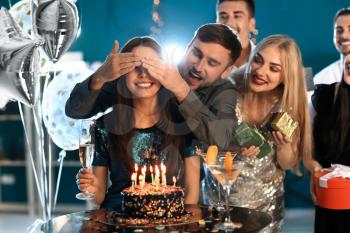 Young woman with friends near her birthday cake at party in club�