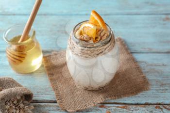 Tasty oatmeal dessert with sliced orange and walnuts in glass jar on wooden background�