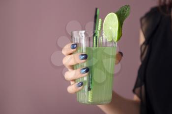 Young woman with beautiful manicure holding glass of beverage on color background, closeup�