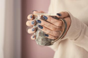 Young woman with beautiful manicure holding cup of beverage, closeup�