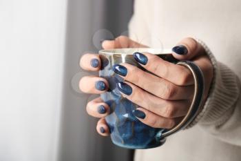 Young woman with beautiful manicure holding cup of beverage, closeup�