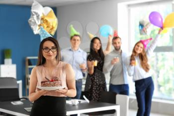 Young woman with birthday cake at party in office�