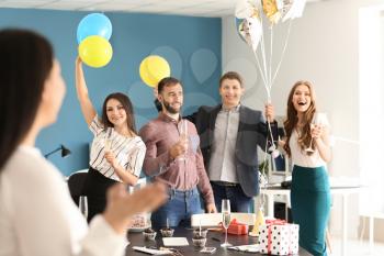 Happy colleagues at surprise party for young woman on her birthday in office�