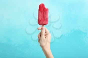 Woman holding delicious strawberry popsicle on color background�