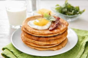 Plate with tasty pancakes, fried egg and bacon on table�