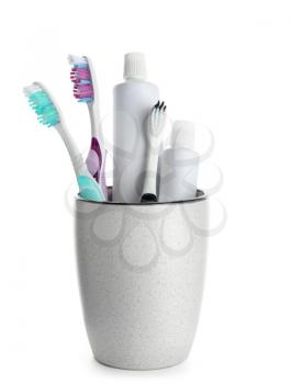 Cup with toothbrushes and paste on white background�