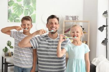 Man and his little children brushing teeth at home�