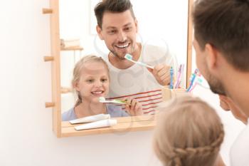 Little girl and her father brushing teeth in bathroom�