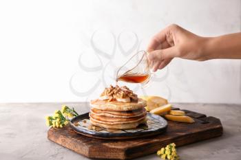Woman pouring syrup onto tasty pancakes�