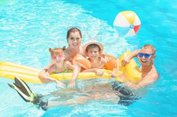 Happy family with inflatable mattress in swimming pool�