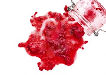 Glass jar and spilled raspberry jam on white background�
