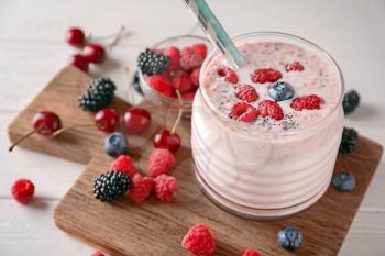 Glass with tasty raspberry smoothie and berries on light table�