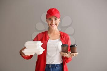 Young woman with plastic containers and cups of coffee on grey background. Food delivery service�