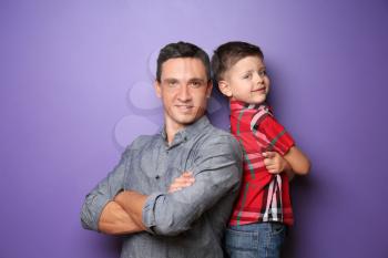 Portrait of little boy and his father on color background�