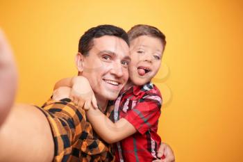 Little boy and his dad taking selfie on color background�