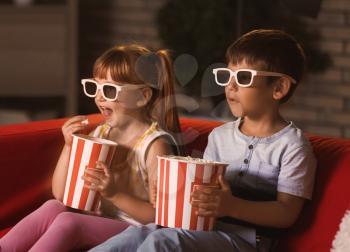 Cute children in 3d glasses watching movie on sofa in evening�