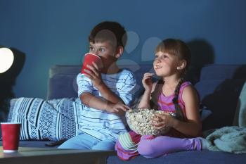 Cute children watching TV on sofa in evening�