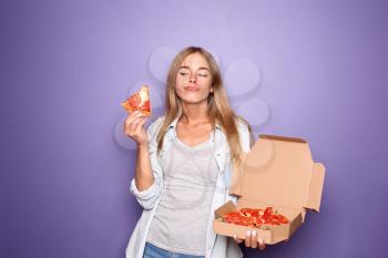 Young woman with delicious pizza on color background�