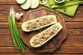 Board with quinoa stuffed zucchini boats and vegetables on wooden table�