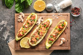 Board with meat stuffed zucchini boats and spices on grunge table�
