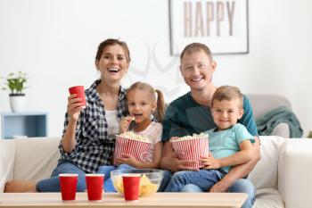 Family eating popcorn while watching TV at home�
