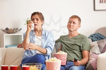Couple eating popcorn while watching soap opera at home�