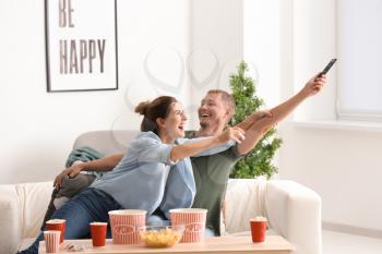 Couple fighting for remote control while watching TV at home�