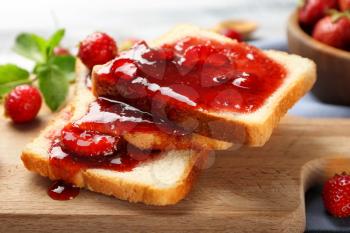 Slices of bread with delicious strawberry jam on board, closeup 