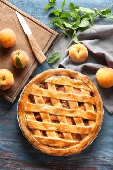 Plate with delicious peach pie on wooden table�