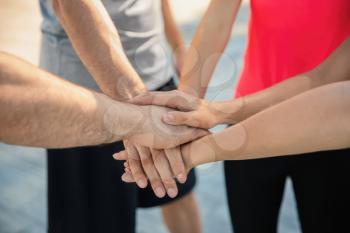 Group of sporty people putting hands together outdoors, closeup�