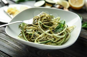 Plate of spaghetti with zucchini and pesto sauce on wooden table, closeup�