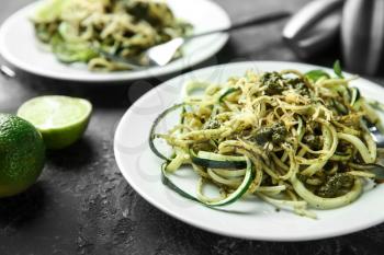 Plate of spaghetti with zucchini, pesto sauce and cheese on table, closeup�