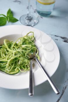 Plate of spaghetti with zucchini and pesto sauce on table, closeup�