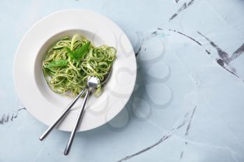 Plate of spaghetti with zucchini and pesto sauce on table�