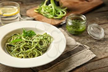 Plate of spaghetti with zucchini and pesto sauce on wooden table�
