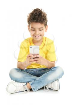 Cute little boy with mobile phone on white background�