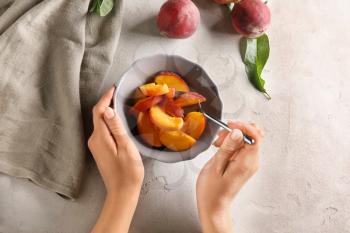 Woman with bowl full of sliced peaches at light table�