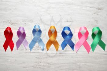 Different colorful ribbons on white wooden background. Cancer concept�