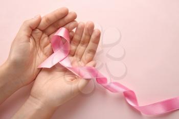 Woman holding pink ribbon on color background. Breast cancer concept�