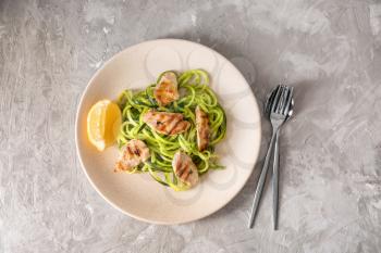 Plate with zucchini spaghetti and meat on light table�
