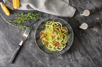 Plate with zucchini spaghetti and mushrooms on grey table�